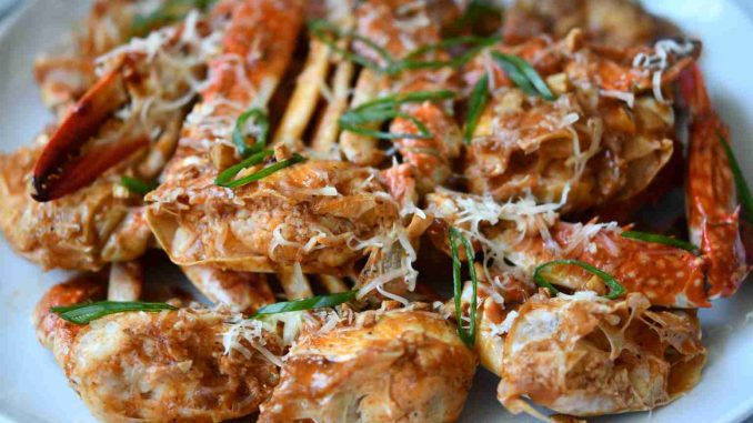 A plate of succulent garlic butter crab garnished with fresh herbs.